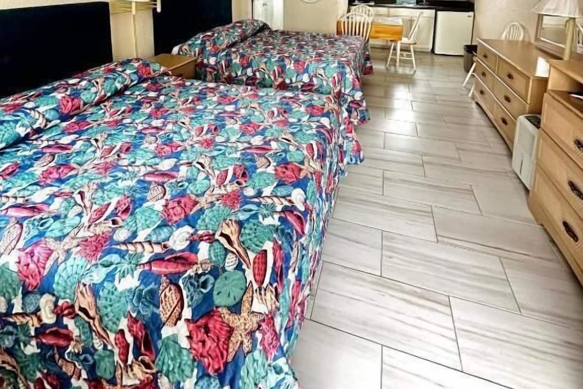 Une chambre d’hôtel avec un grand lit, un bureau, une chaise, un four à micro-ondes et une kitchenette.