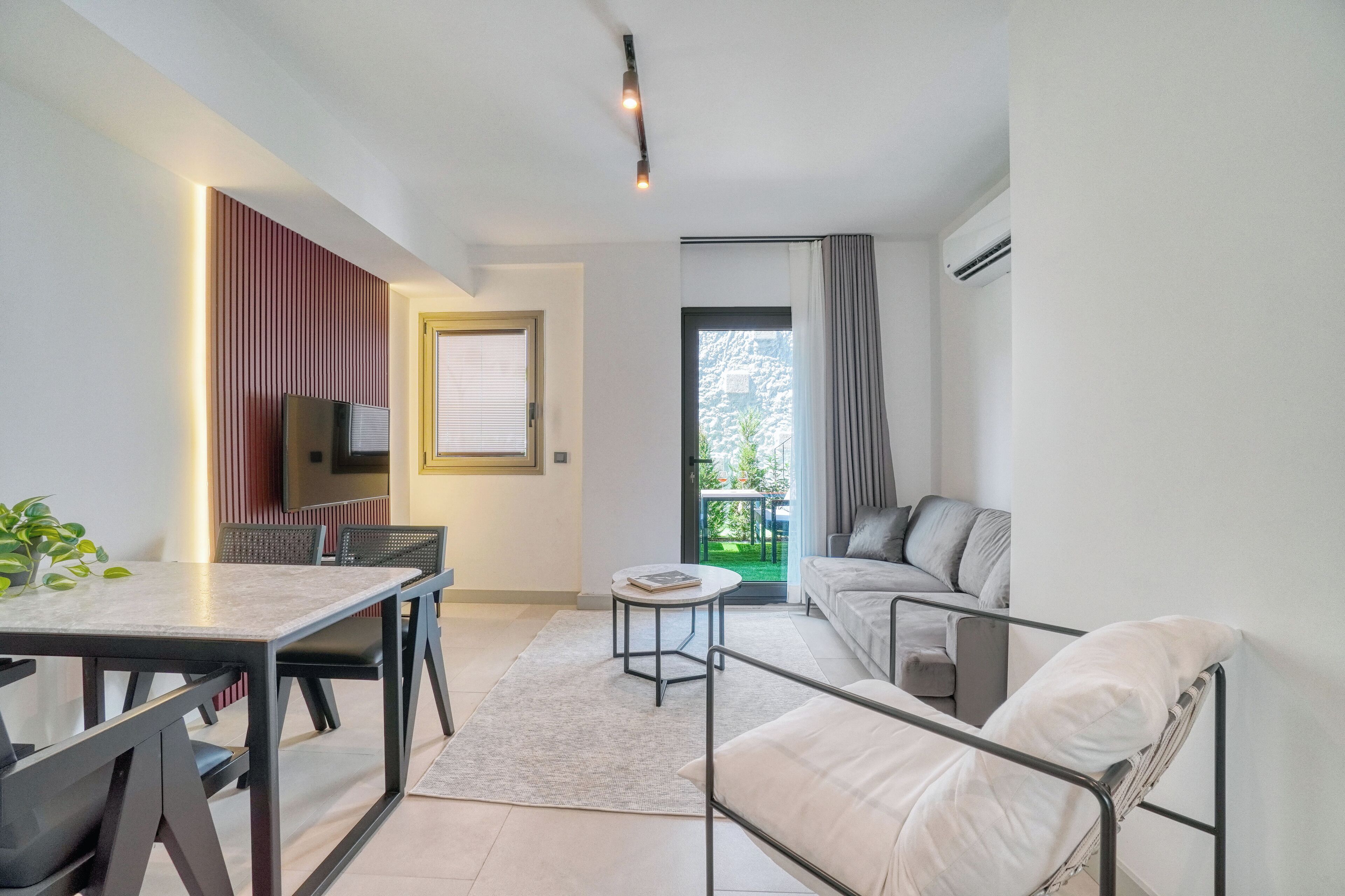 Una sala moderna con comedor, un sofá, un televisor y un balcón con vistas.