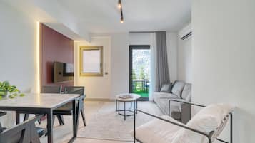 Una sala moderna con comedor, un sofá, un televisor y un balcón con vistas.