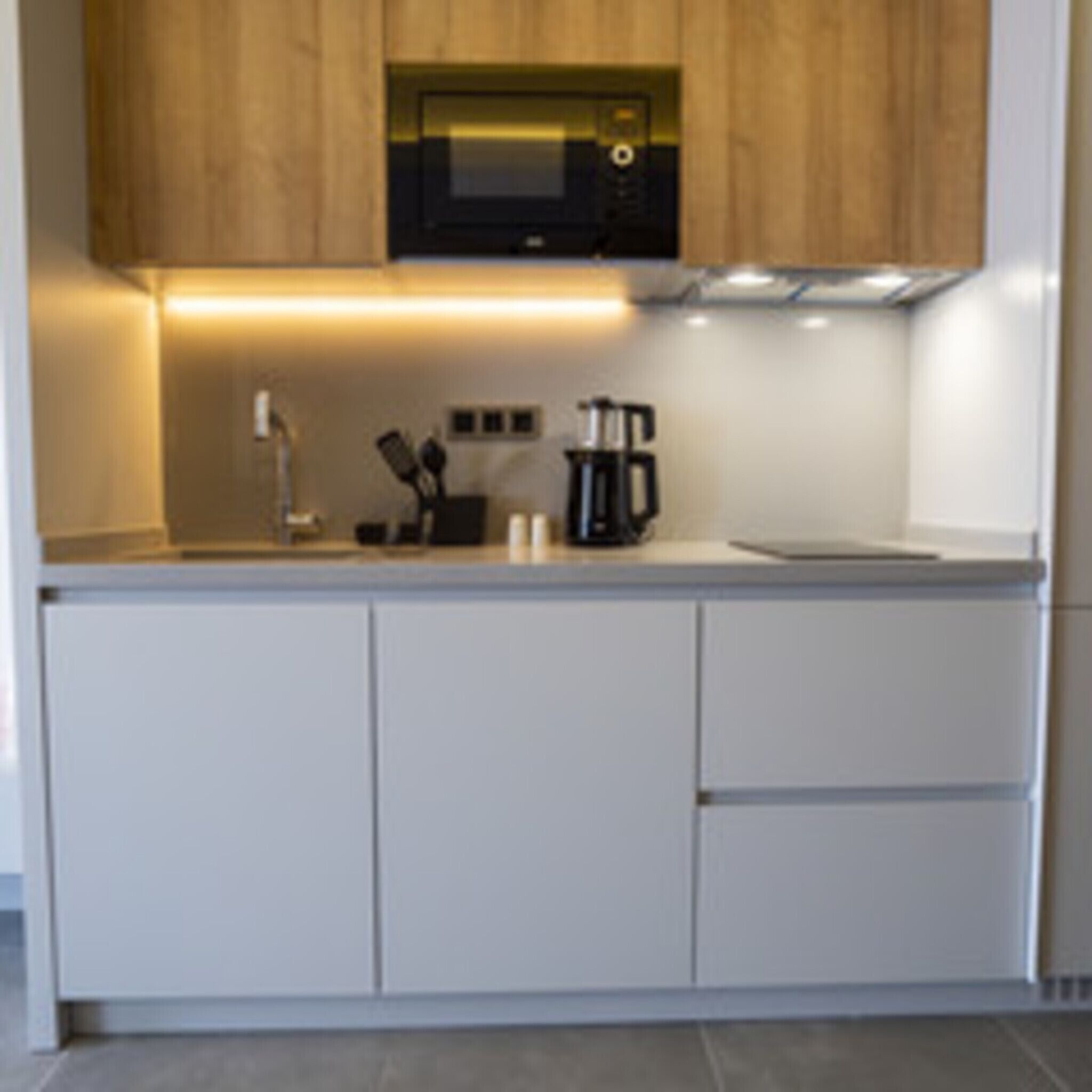 A modern kitchen with a microwave, coffee maker, and cabinets.