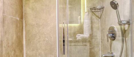Eine moderne Dusche mit Glastür, Handbrause, Wandarmatur und Handtuchhalter.