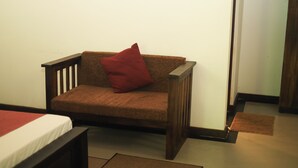 Ein kleiner, gemütlicher Raum mit einem einzelnen braunen Sofa an einer schlichten Wand, einer hölzernen Bank und einer Fußmatte auf dem Boden.