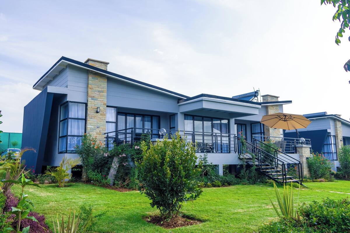 A modern two-story house with a stone facade, large windows, and a well-maintained garden.