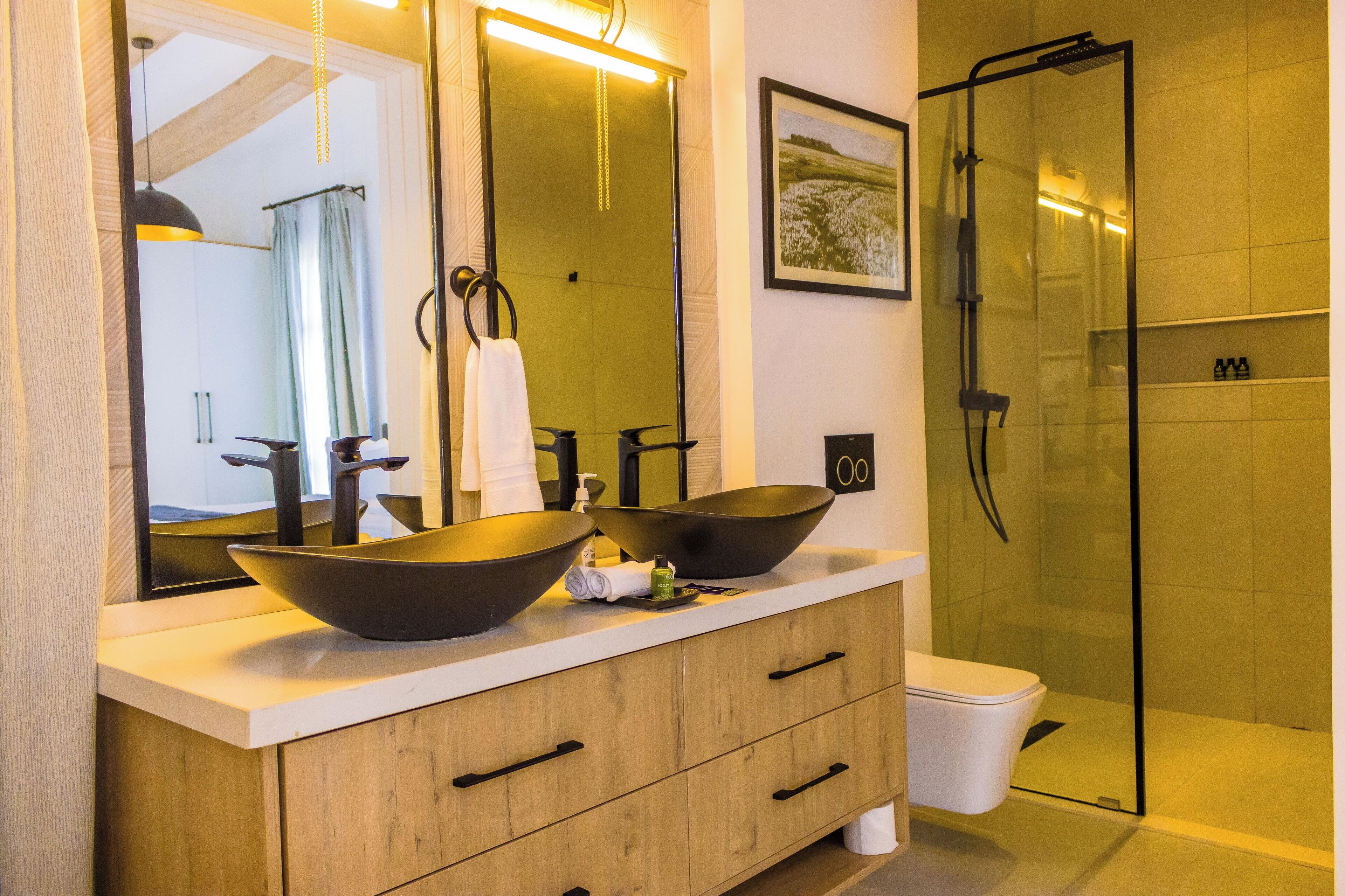 Une salle de bain avec un double lavabo, un grand miroir, une cabine de douche en verre et des meubles en bois.
