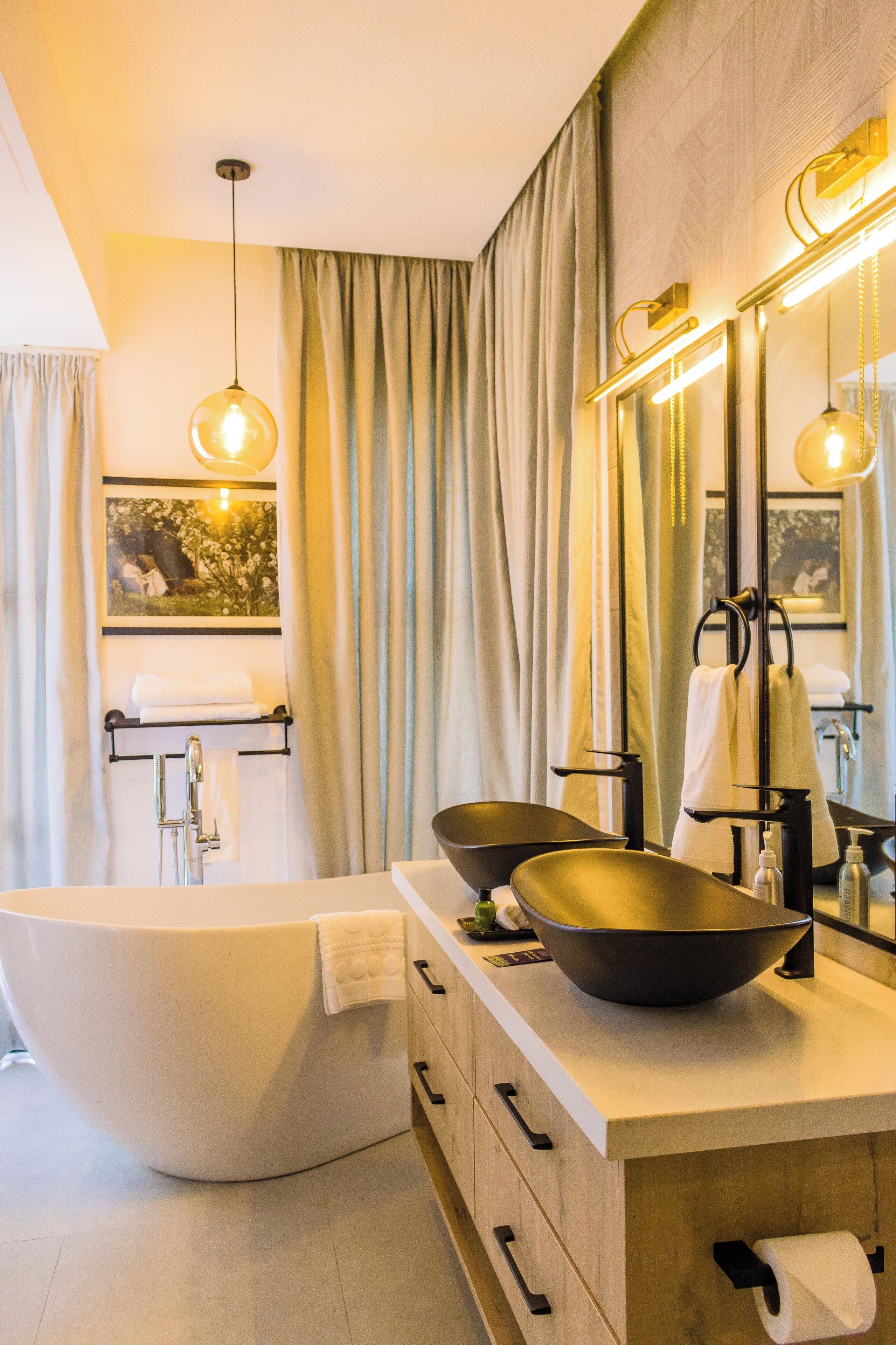 Ein modernes Badezimmer mit einer freistehenden Badewanne, einem Doppelwaschtisch mit großem Becken und einem Spiegel mit integrierter Beleuchtung.