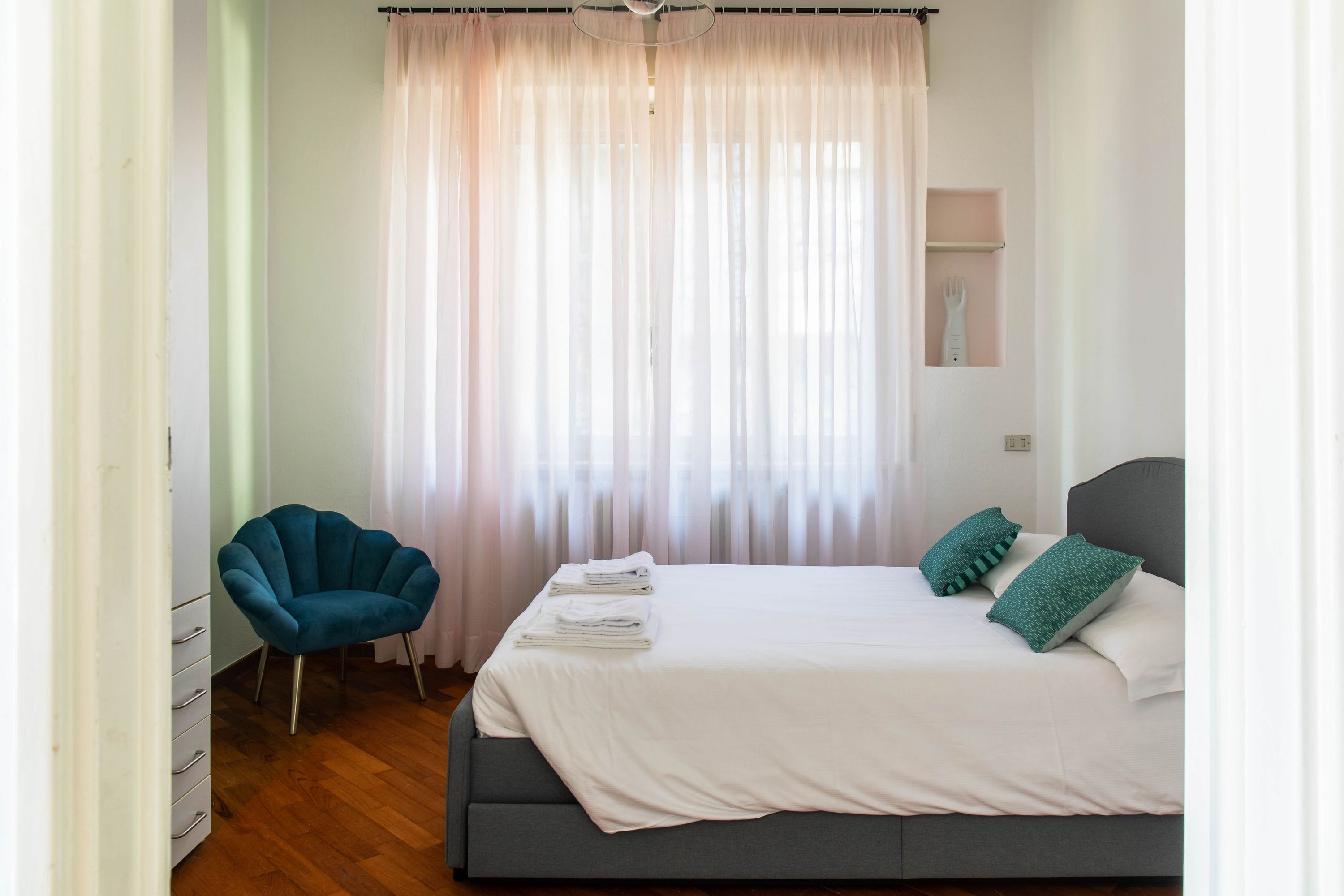 Ein Schlafzimmer mit einem Bett, einem Sessel und einem kleinen Regal mit einer Gabel.