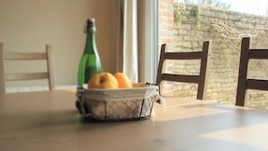 Une table à manger avec un panier de fruits et une bouteille.