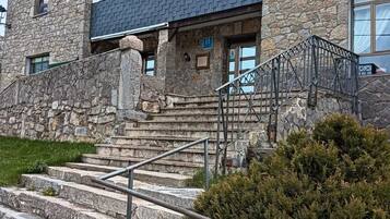 A stone building with a staircase leading to a door marked with an 'H'.