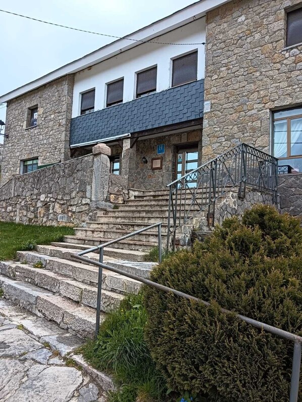 Un edificio de piedra con una escalera que lleva a una puerta marcada con una 'H'.