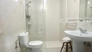 A bathroom with a toilet, bidet, sink, and shower.