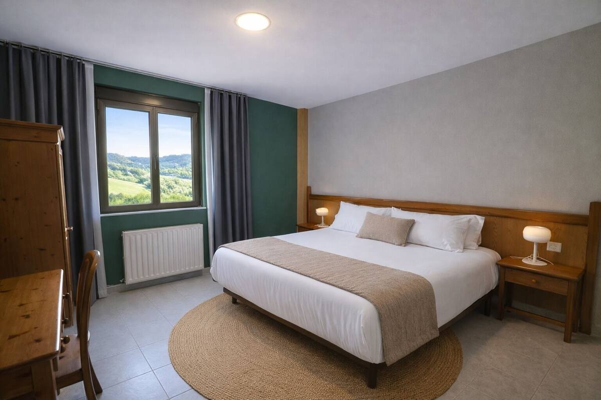 Une chambre d’hôtel avec un lit, des lampes de chevet, une vue sur la verdure, une armoire en bois et un tapis rond.
