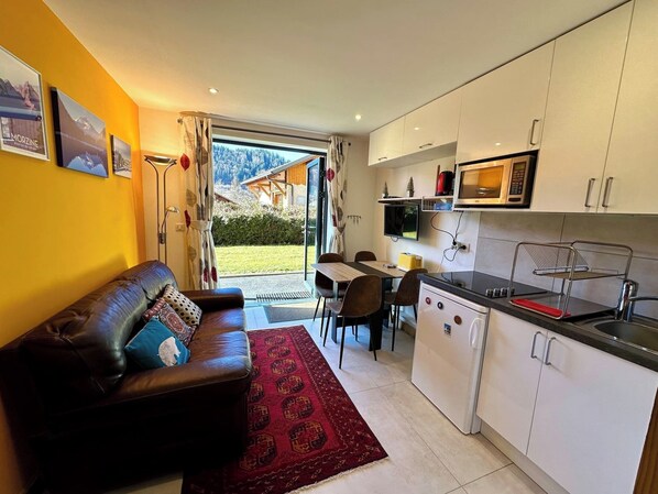Ein kompakter Wohnbereich mit Sofa, Esstisch und Küchenzeile.