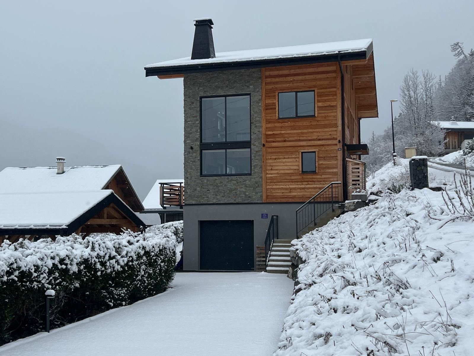 A modern two-story building with a snow-covered roof and a visible garage door.