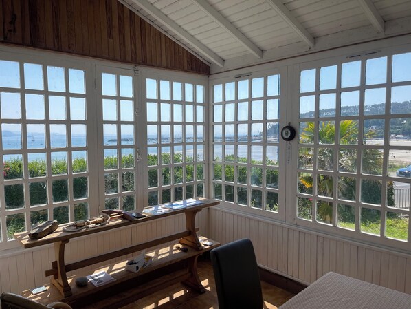 A room with large windows, a wooden bench, and a table with various items. - Maison de Famille 6 Personnes en Face de la Plage de Morgat, vue Exceptionnelle (Crozon)