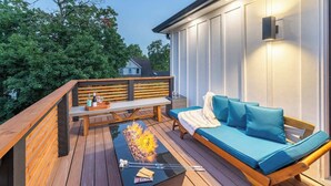 Eine Terrasse mit Feuerstelle, einer Holzbank und einem blauen Sofa.