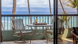A balcony with a table and chairs, overlooking the ocean. - Oceanfront spacious 2 bedroom condo, updated, private beach, walkable area (Napili-Honokowai)