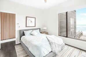Een moderne slaapkamer met een bed, een nachtkastje, een ingelijst schilderij, een raam met uitzicht en een houten paneel aan de muur.