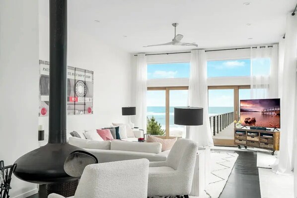 Een moderne woonkamer met een open haard, een bank, een televisie en uitzicht op de oceaan.