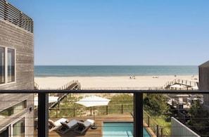 A modern building with a pool and a beach view.