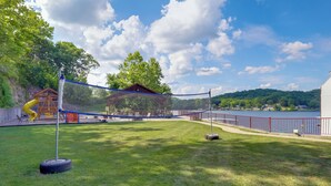 A backyard with a netted play area, a tire swing, and a wooden playhouse. - Lake of The Ozarks Condo w/ Pool in Camdenton (Camdenton)