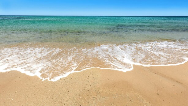 Una playa con agua turquesa cristalina y una orilla arenosa.