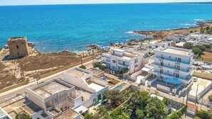 Un pueblo costero con edificios modernos, una torre histórica y una vista despejada del mar.