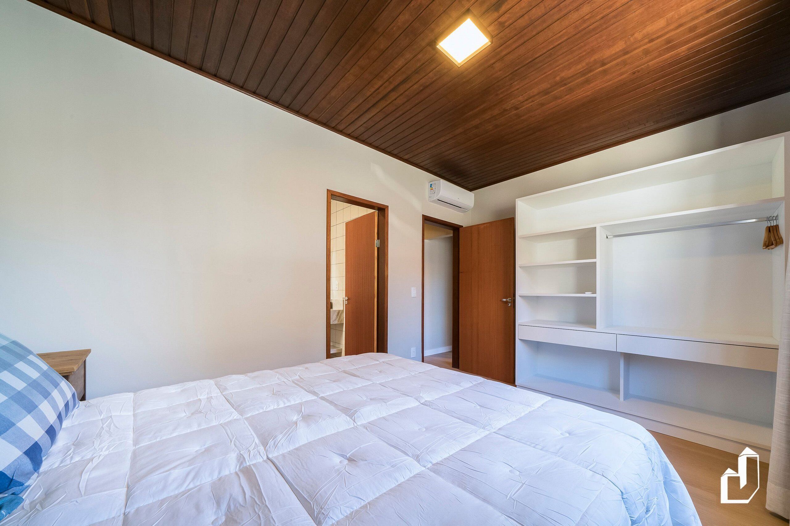 A bedroom with a bed, wooden ceiling, built-in wardrobe, and an air conditioning unit.