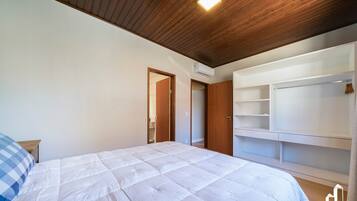 A bedroom with a bed, wooden ceiling, built-in wardrobe, and an air conditioning unit.