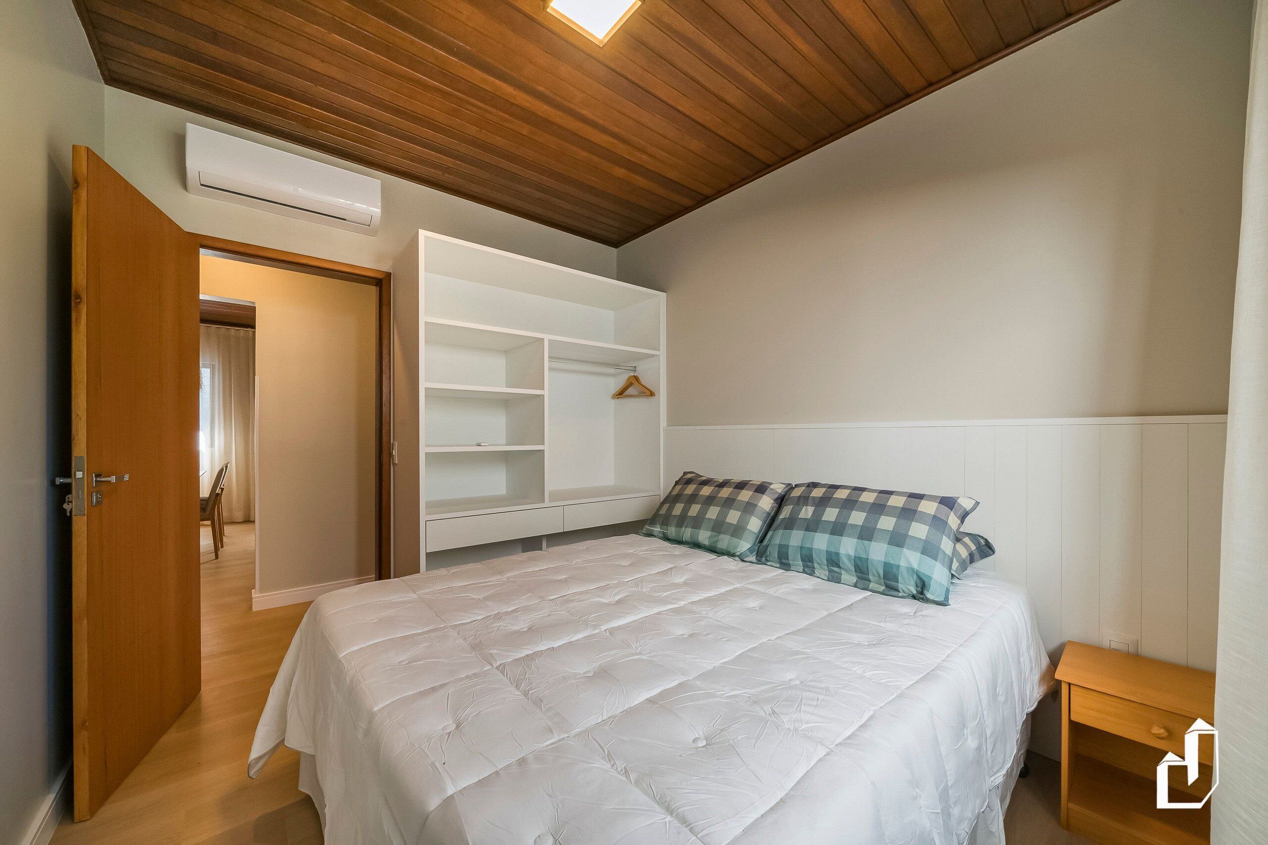 A bedroom with a bed, a wardrobe, a bedside table, and a ceiling light.