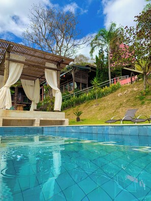 A pool area with a pergola and lounge chairs. - Pousada Verde Villas  (Brumadinho)