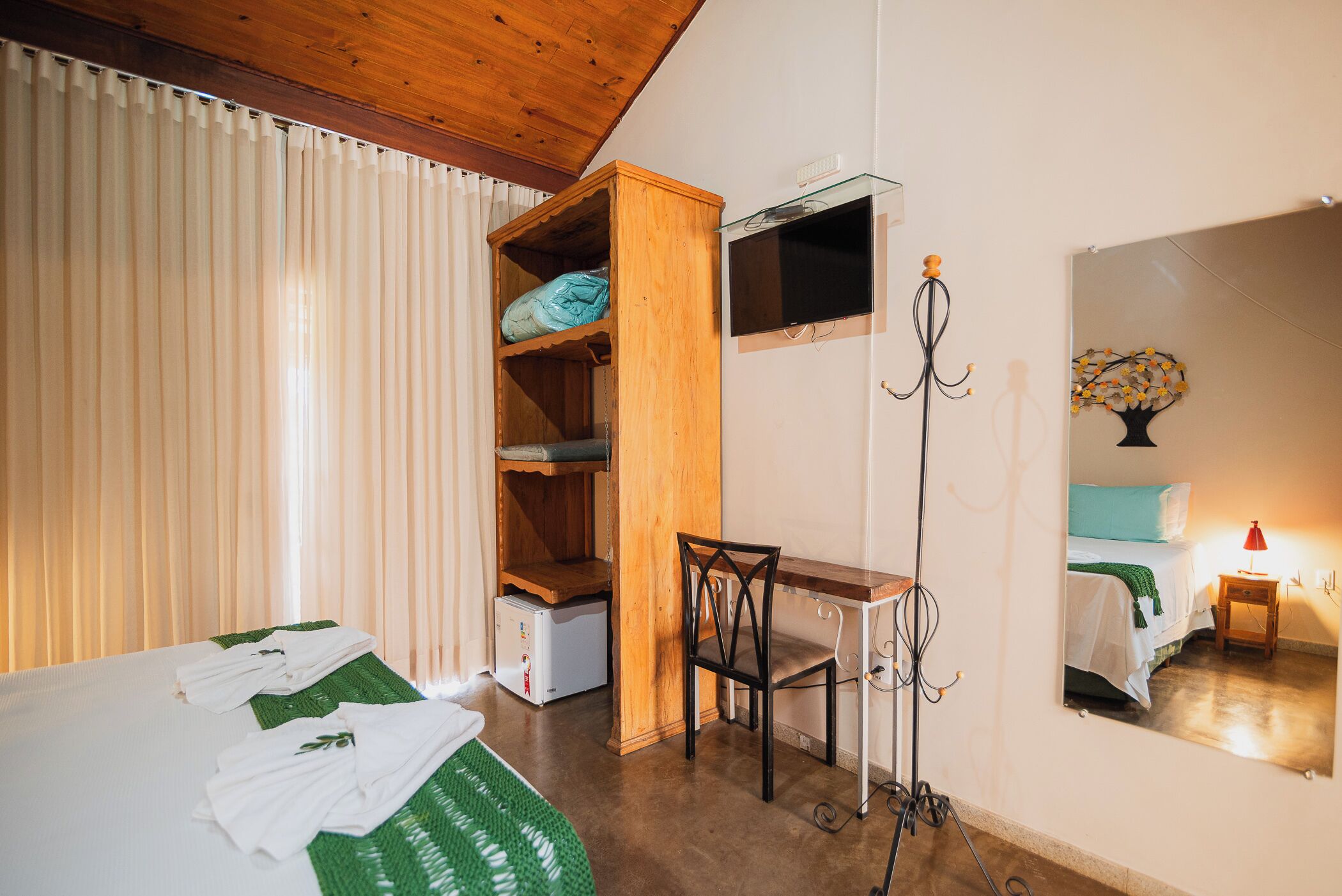 Quarto com cama, escrivaninha, cadeira, guarda-roupa e espelho.