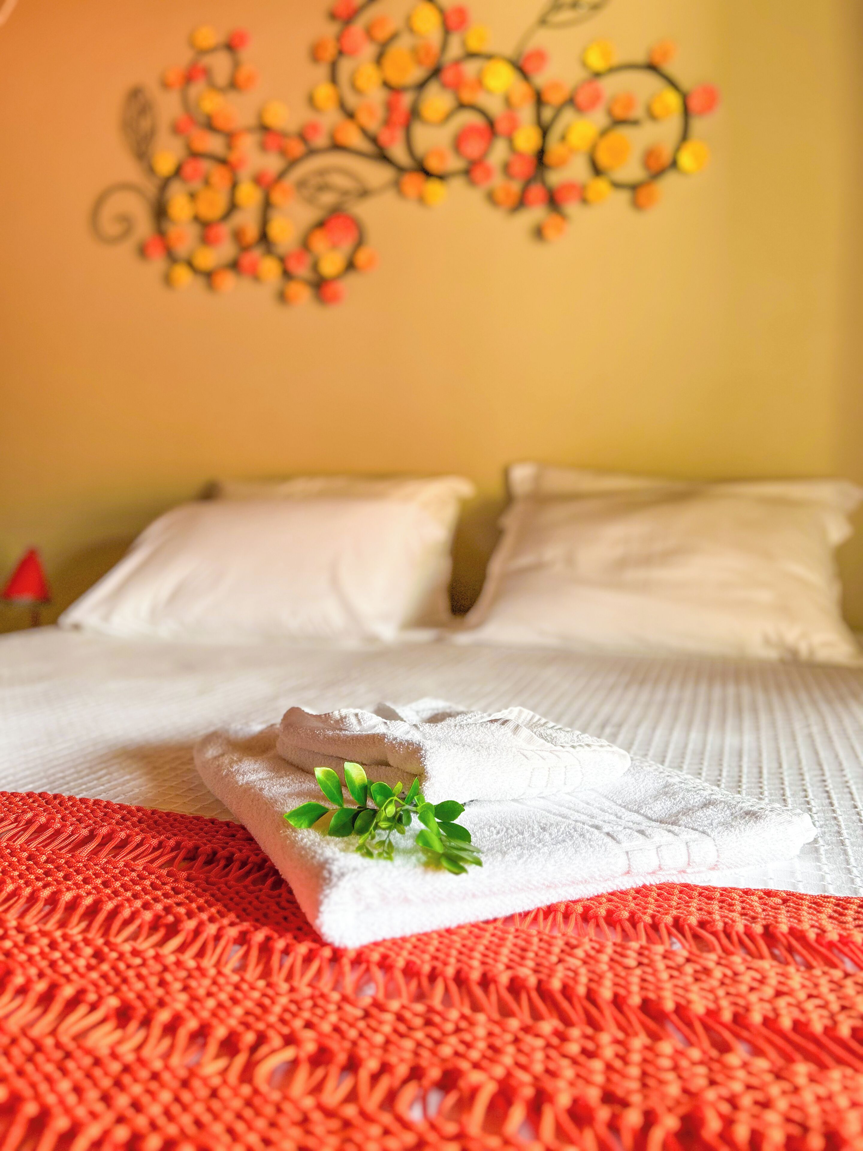 A neatly made bed with white linens and a red woven blanket.