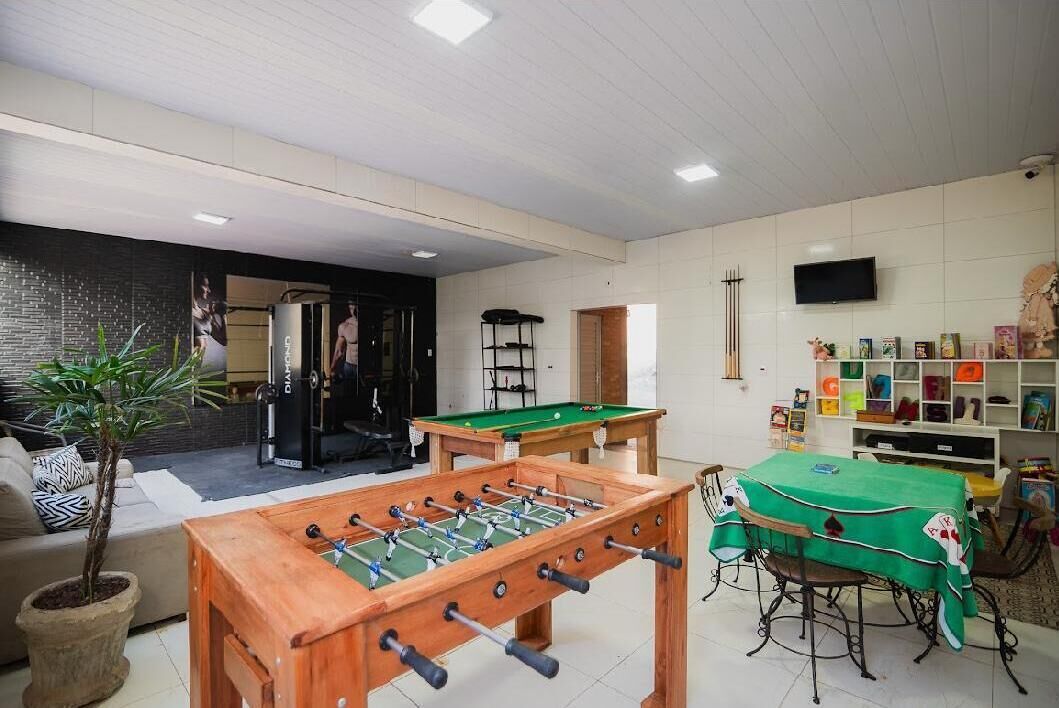 Um quarto com mesa de pebolim, mesa de bilhar e televisão.