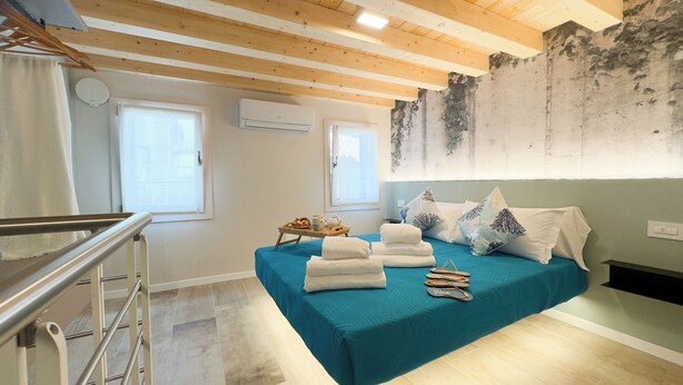 Un dormitorio con cama, toallas, una bandeja de desayuno y vistas al exterior.