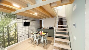 Una cocina moderna con microondas integrado, un comedor con mesa y sillas, y una escalera que lleva a un nivel superior.