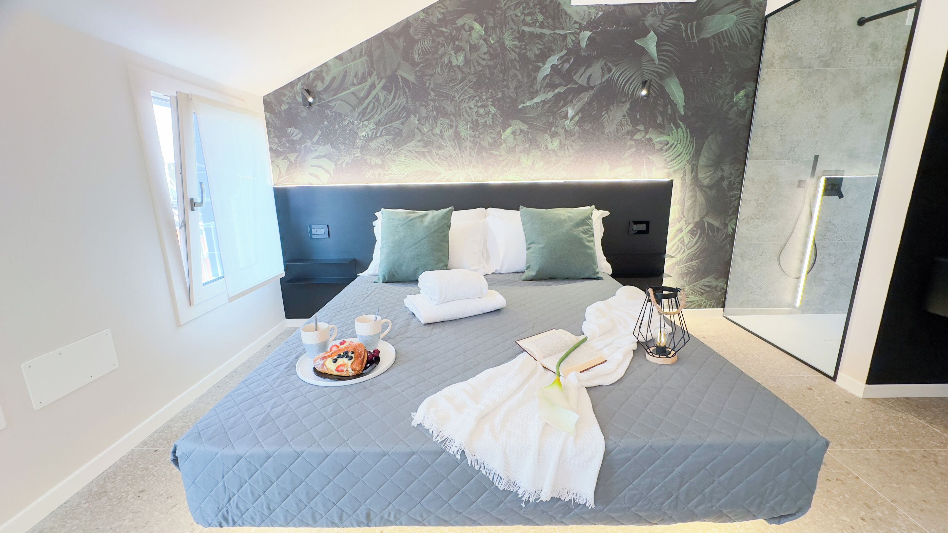 Une chambre moderne avec un grand lit, une table de chevet, une commode et une lampe fixée au mur.