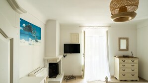 A room with a fireplace, a television, a dresser, and a painting on the wall. - Casa Alina by Wonderful Italy (Fasano)