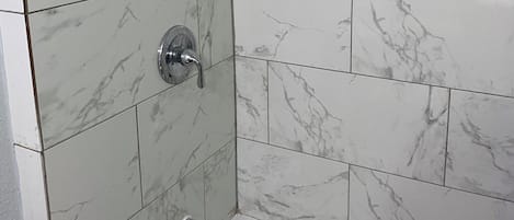 Bañera con ducha, toallas, papel higiénico