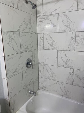 Kombinasi shower/bathtub, handuk, dan tisu toilet