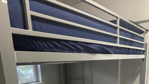 Una cama litera con ventana, una escalera y un pequeño estante.