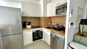 Cozinha moderna com armários brancos, geladeira Bosch, micro-ondas e lava-louças.