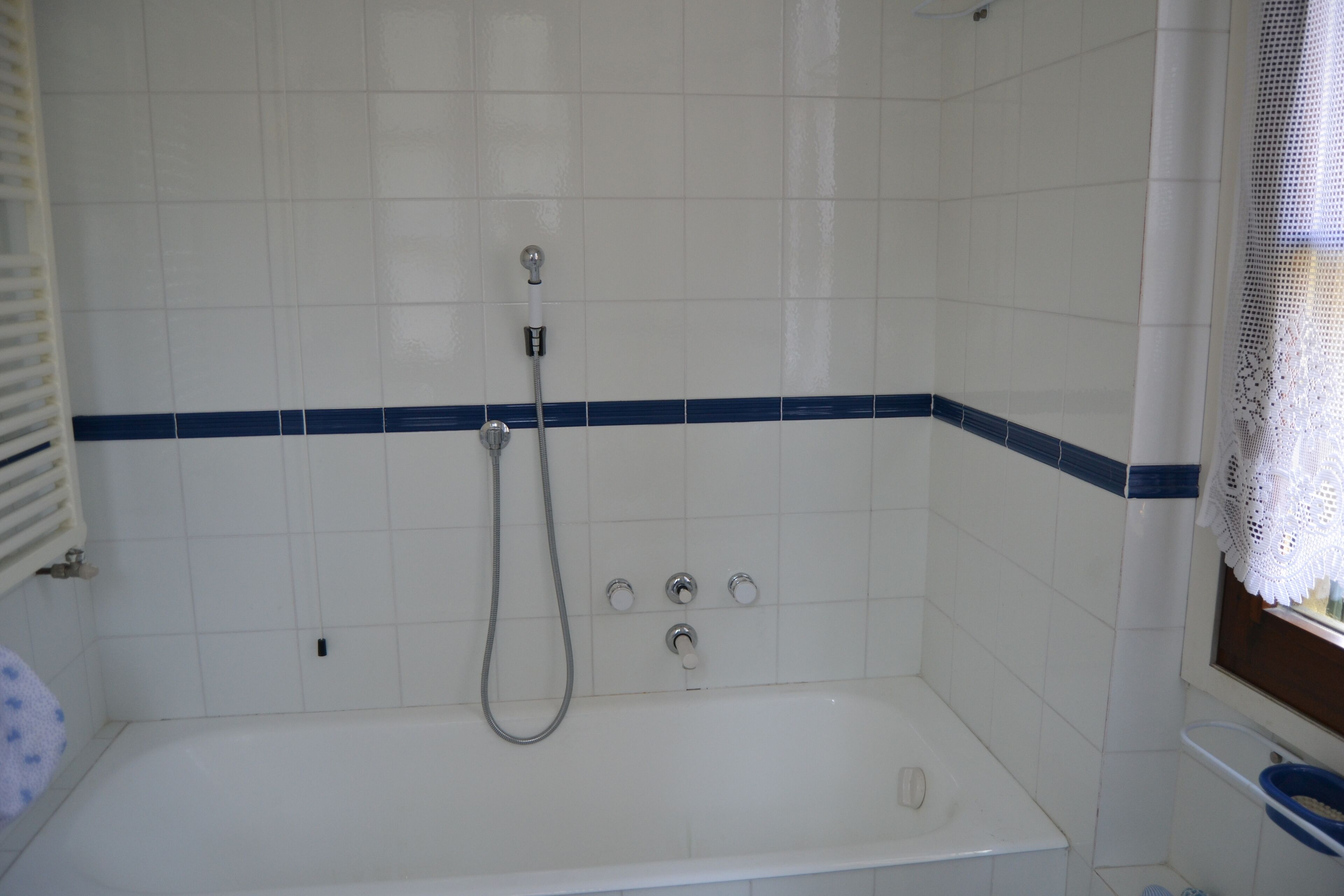 Ein Badezimmer mit einer weißen Badewanne, einer Duschbrause und einem Handtuchhalter.