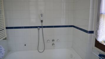 Ein Badezimmer mit einer weißen Badewanne, einer Duschbrause und einem Handtuchhalter.