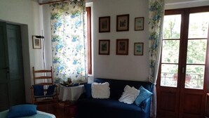 A room with a bed, a sofa, a chair, a table, and a window with curtains. - Elegant private room with lake view balcony (Castelveccana)