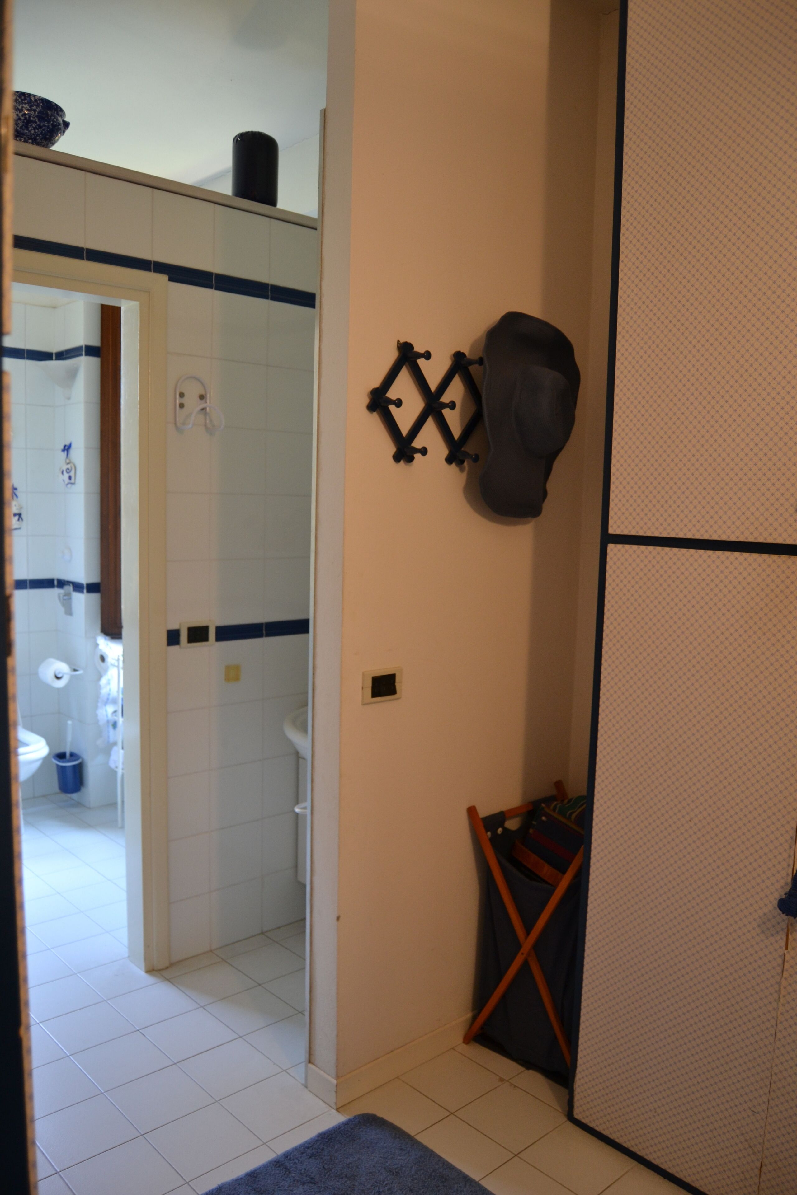 Ein Badezimmer mit Dusche, Toilette und Waschbecken. Ein Handtuchhalter und eine kleine Ablagefläche mit Pflegeprodukten sind vorhanden.