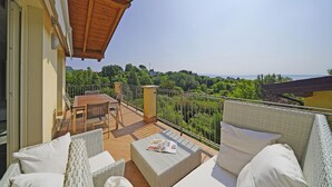 A balcony with wicker furniture, a table, and chairs. - Montecolo Resort E7 by Wonderful Italy (Manerba del Garda)