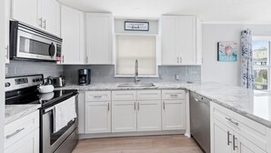 Una cocina moderna con armarios blancos, electrodomésticos de acero inoxidable y encimera de mármol.