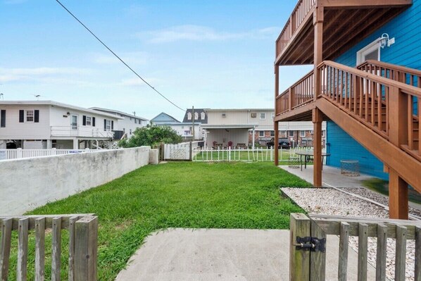 A residential area with a grassy yard, a concrete pathway, and a wooden deck with a railing.