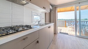 Una cocina moderna con estufa a gas, un fregadero y vistas a un balcón con mobiliario exterior.