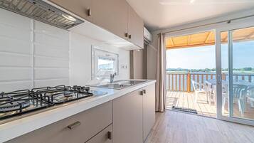 A modern kitchen with a gas stove, a sink, and a view of a balcony with outdoor furniture.
